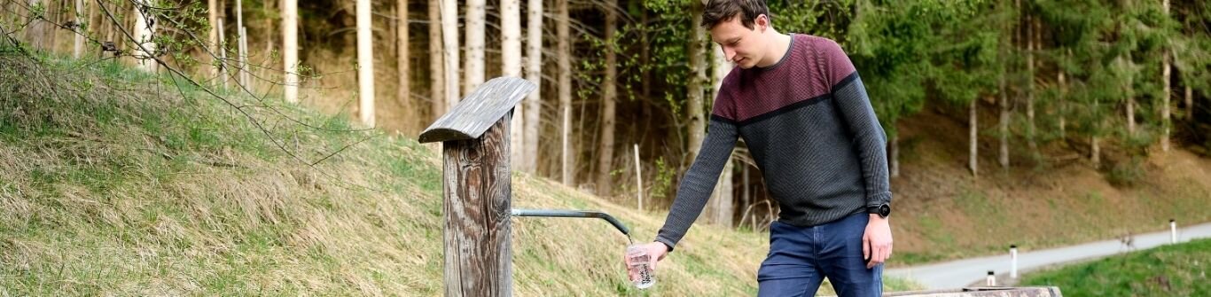 Mann füllt Wasser beim Brunnen auf